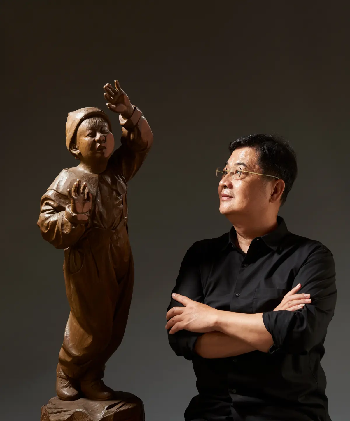 2019 年,陳啓村獲「台灣木雕薪傳成就獎」,與 1995 年作品〈窗〉合影。這件作品將孩子手、臉緊貼玻璃櫥窗,探看商品的好奇神情刻畫得入木三分,現由奇美博物館典藏。(圖片來源/陳啓村) 2019 年,陳啓村獲「台灣木雕薪傳成就獎」,與 1995 年作品〈窗〉合影。這件作品將孩子手、臉緊貼玻璃櫥窗,探看商品的好奇神情刻畫得入木三分,現由奇美博物館典藏。(圖片來源/陳啓村)