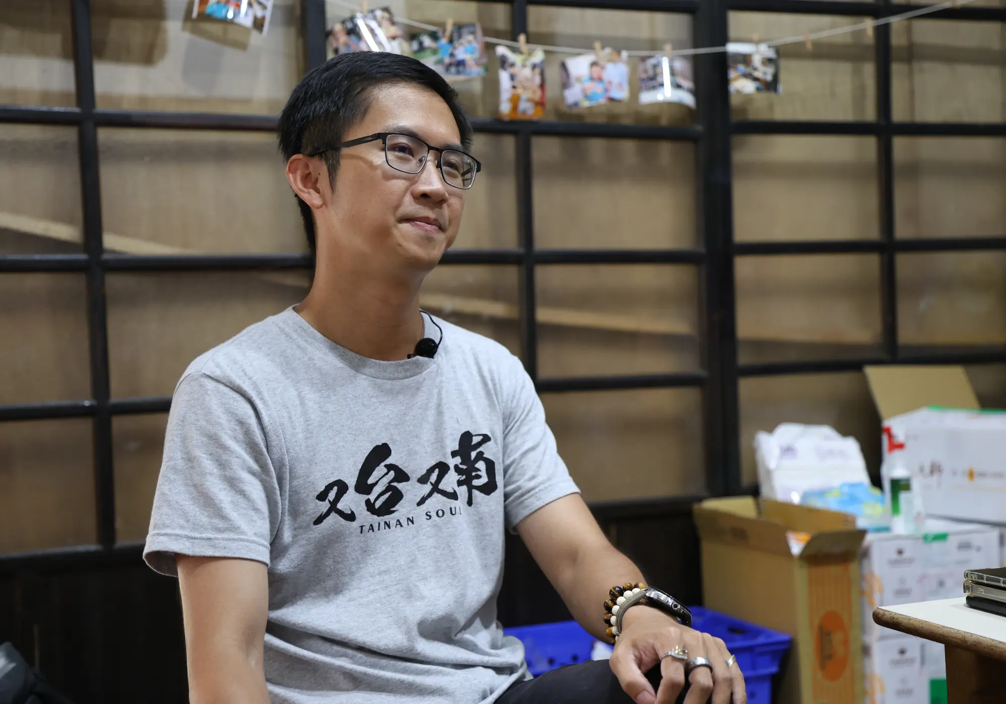 黃雅聖坐在璞育塾堆滿救災物資的教室接受採訪，不管是牆壁上與孩子的照片還是地上民眾捐贈的物資，都代表著璞育塾承載了地方深厚的信任。（攝影／葉仁琛）